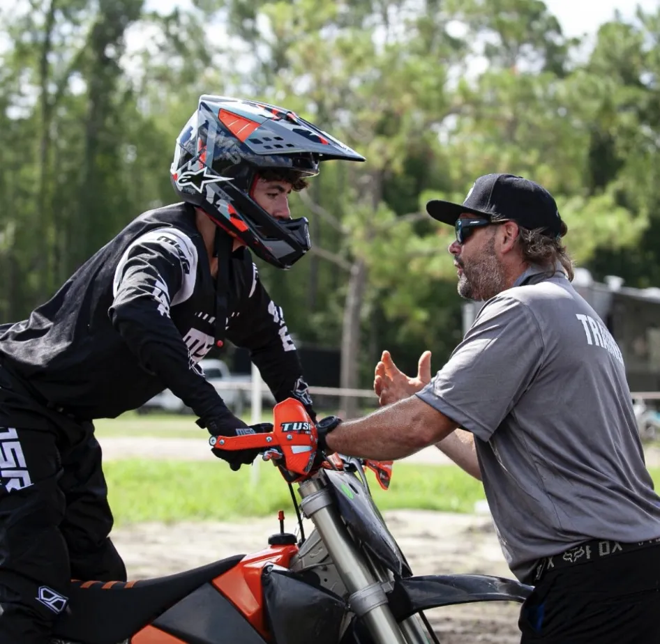 Mike coaching a rider one on one at the handlebars between laps